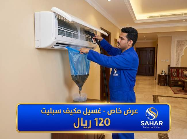 عرض غسيل مكيف سبليت بـ 120 ريال من شركة سهر العالمية بجدة - فني محترف بالزي الأزرق يقوم بتنظيف المكيف بالبخار باستخدام كيس تجميع المياه المتسخة داخل شقة فاخرة في جدة